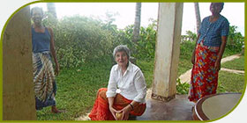 Locals helping Brenda master the art of scraping coconuts.